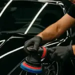 Operatore esegue lucidatura con rotorbitale su Porsche nera in garage moderno a Carmagnola
